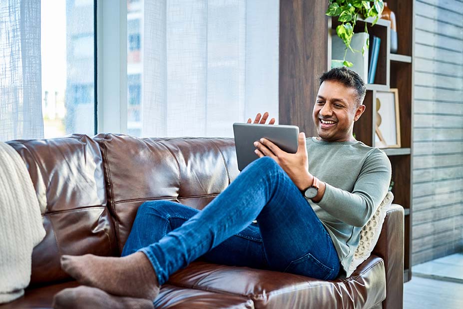 man relaxing on couch with tablet